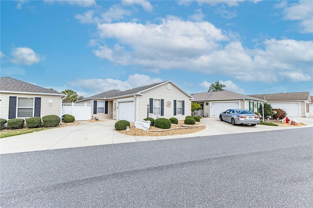 ranch-style house featuring concrete driveway, an attached garage, and fence