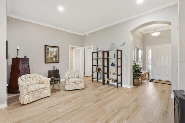 living area featuring light wood-style floors, arched walkways, crown molding, and baseboards