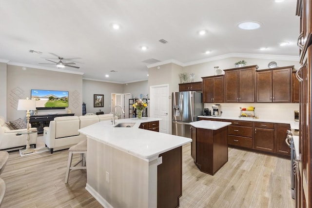 kitchen featuring visible vents, appliances with stainless steel finishes, a kitchen island with sink, a sink, and light wood-type flooring