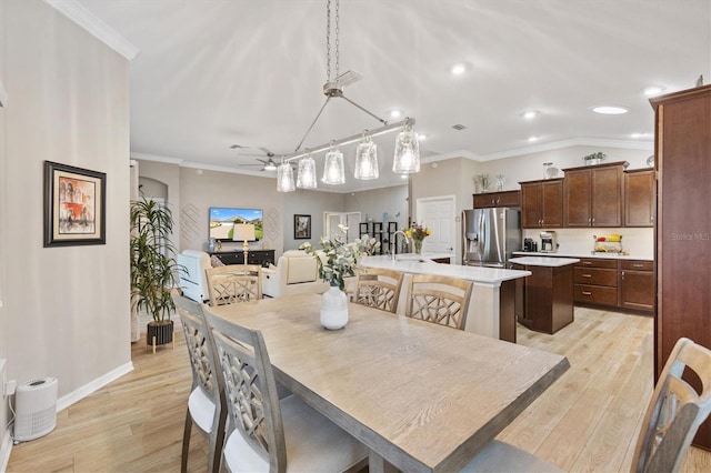 dining area with baseboards, ceiling fan, light wood-style flooring, and crown molding