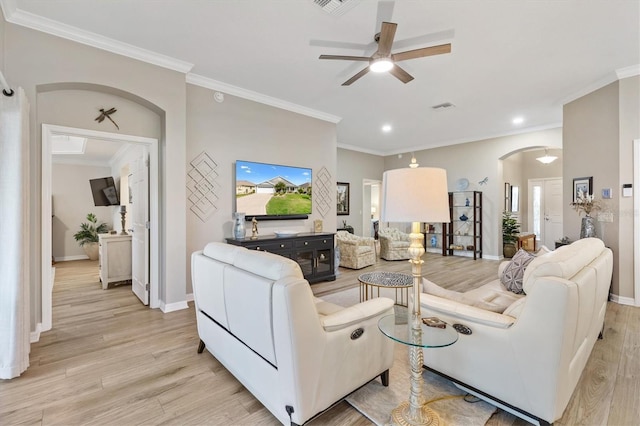 living room with arched walkways, visible vents, baseboards, light wood-style floors, and crown molding