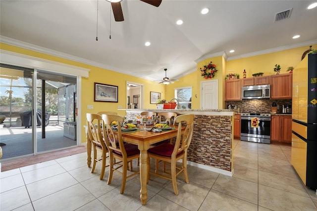 dining room with light tile patterned floors, visible vents, a healthy amount of sunlight, and crown molding