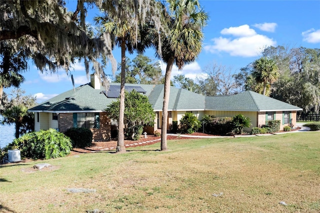 single story home with a front yard, a chimney, and solar panels