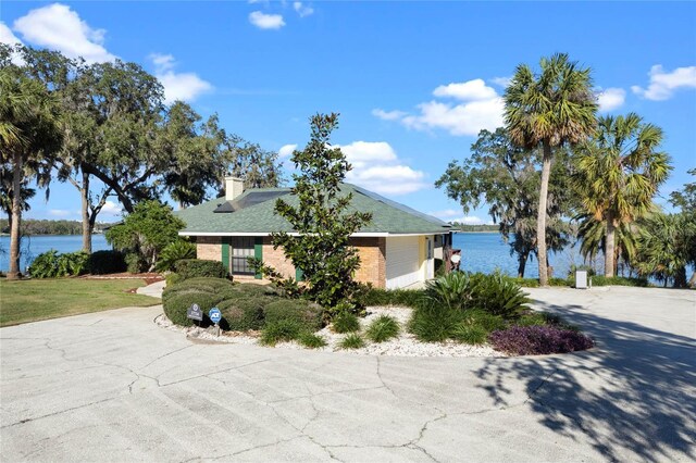 ranch-style home featuring concrete driveway, a water view, brick siding, and an attached garage