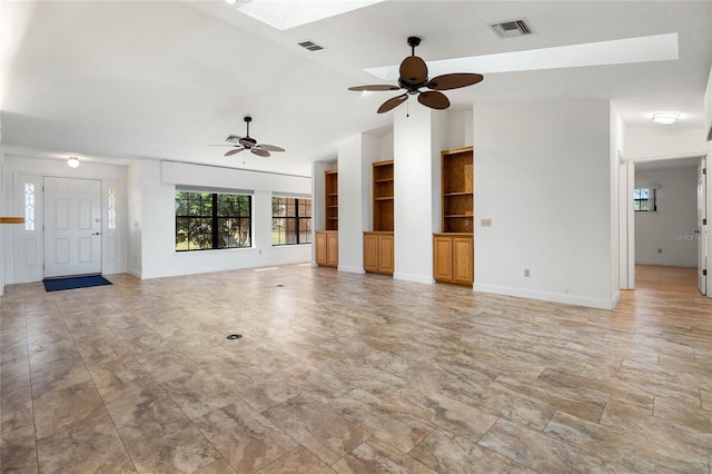 unfurnished living room featuring built in shelves, vaulted ceiling with skylight, visible vents, and a ceiling fan