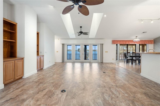 unfurnished living room with lofted ceiling, ceiling fan, visible vents, and baseboards