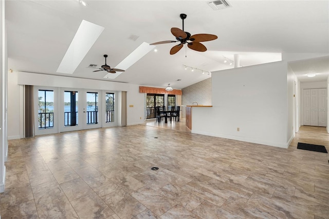 unfurnished living room with vaulted ceiling with skylight, visible vents, and baseboards