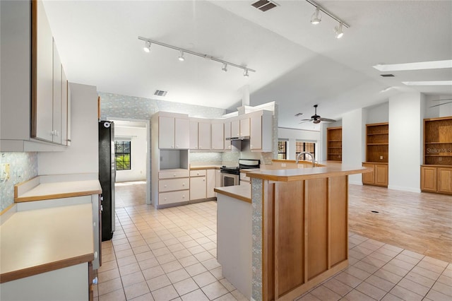 kitchen with light tile patterned floors, vaulted ceiling, visible vents, and stainless steel appliances