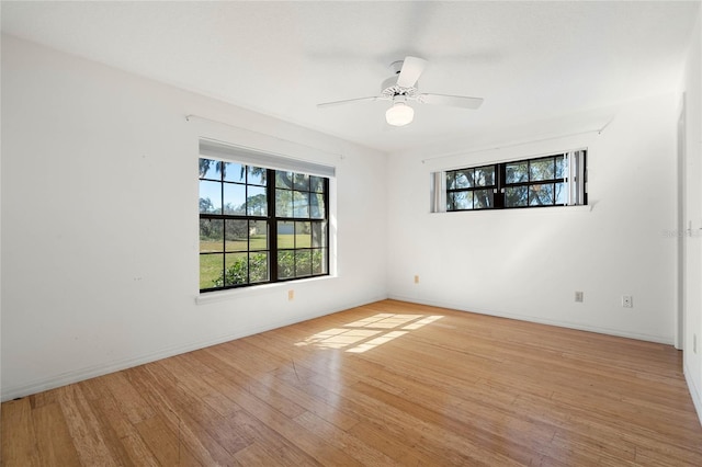 spare room with light wood-style floors, baseboards, and a ceiling fan