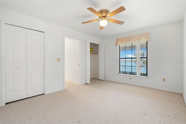 unfurnished bedroom with carpet floors, a ceiling fan, baseboards, and two closets