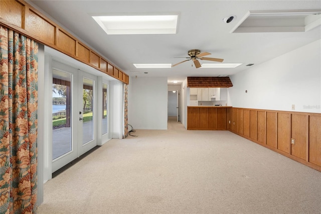 interior space featuring light carpet, a skylight, visible vents, a ceiling fan, and french doors