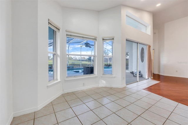 entryway with recessed lighting, a towering ceiling, baseboards, and light tile patterned floors