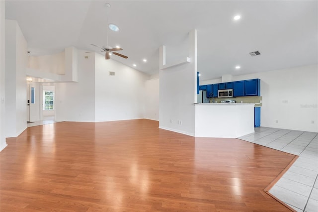 unfurnished living room featuring high vaulted ceiling, light wood finished floors, visible vents, and a ceiling fan