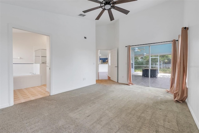 unfurnished bedroom featuring access to exterior, carpet, visible vents, a towering ceiling, and ensuite bathroom