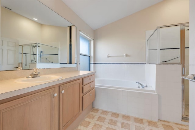 bathroom featuring lofted ceiling, vanity, a shower stall, and a garden tub