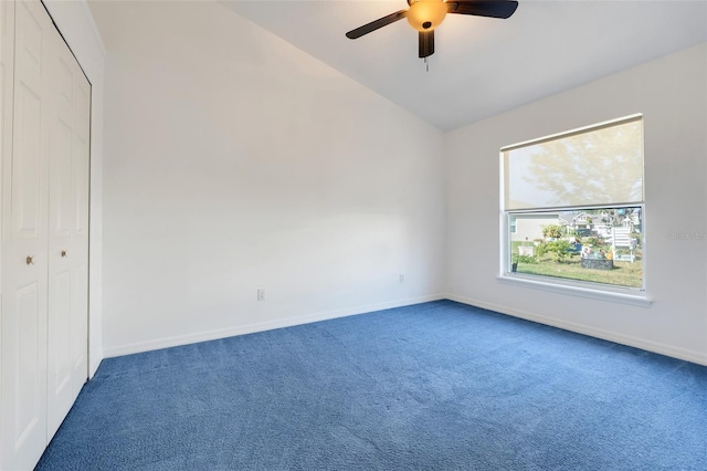 spare room with vaulted ceiling, carpet floors, a ceiling fan, and baseboards