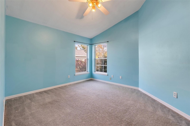 carpeted empty room with vaulted ceiling, a ceiling fan, and baseboards