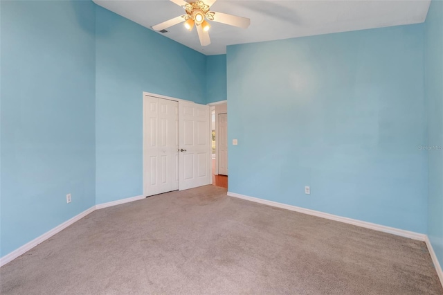 unfurnished bedroom with ceiling fan, a closet, carpet, and baseboards