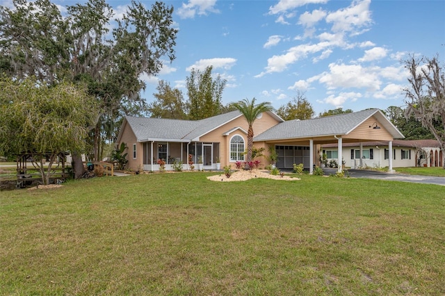 ranch-style house with driveway, a front lawn, an attached garage, and a sunroom