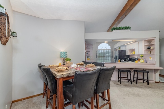 dining space with vaulted ceiling with beams, baseboards, and light colored carpet