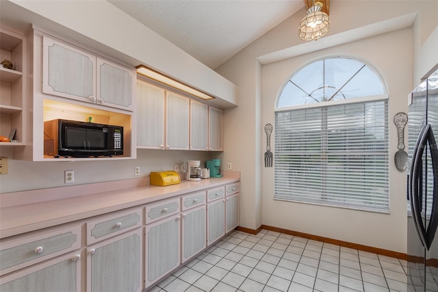 kitchen featuring black microwave, lofted ceiling, light countertops, freestanding refrigerator, and open shelves