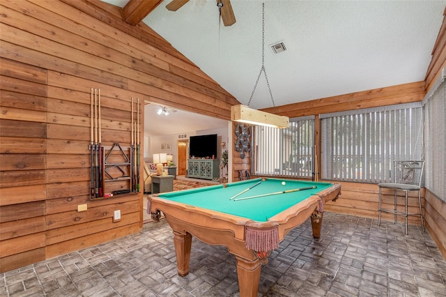 game room with wooden walls, visible vents, vaulted ceiling, and a ceiling fan