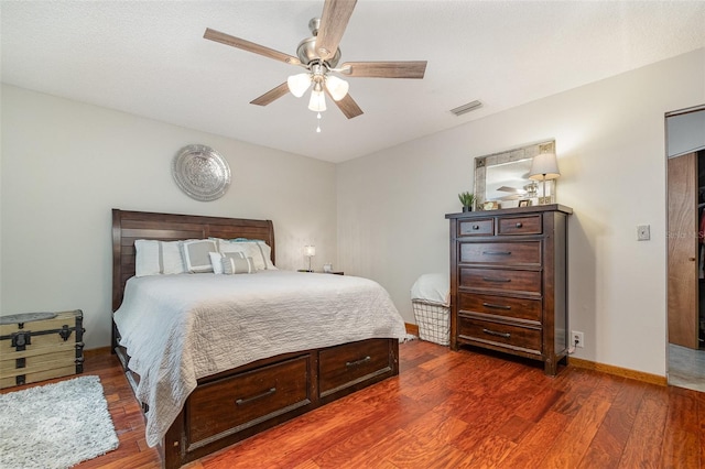 bedroom featuring a ceiling fan, visible vents, baseboards, and wood finished floors