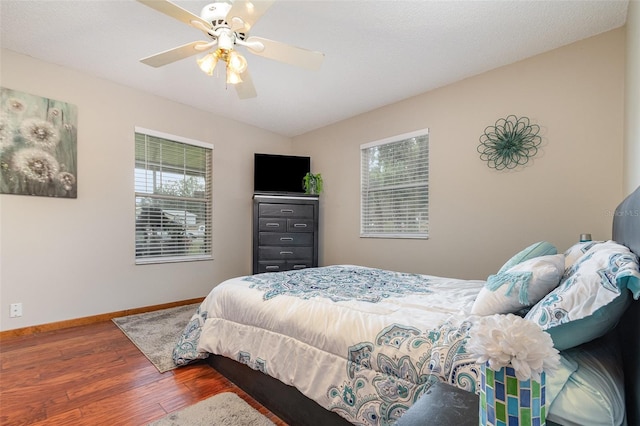 bedroom featuring a ceiling fan, baseboards, and wood finished floors