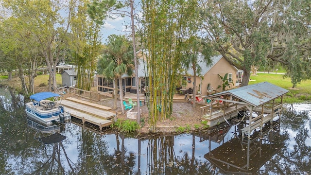 view of dock with a deck with water view, boat lift, and a lawn