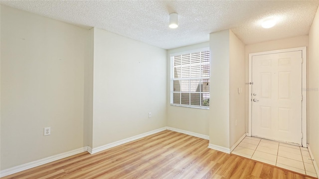 unfurnished room with light wood-style flooring, baseboards, and a textured ceiling