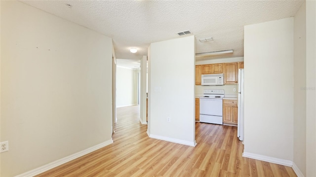 interior space with light wood-type flooring, baseboards, and a textured ceiling