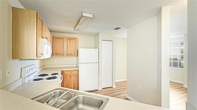 kitchen featuring visible vents, light countertops, white appliances, a textured ceiling, and a sink