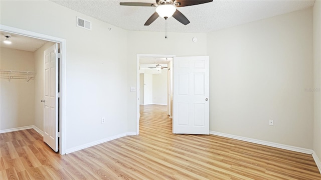 unfurnished bedroom featuring visible vents, light wood-style flooring, a textured ceiling, and baseboards