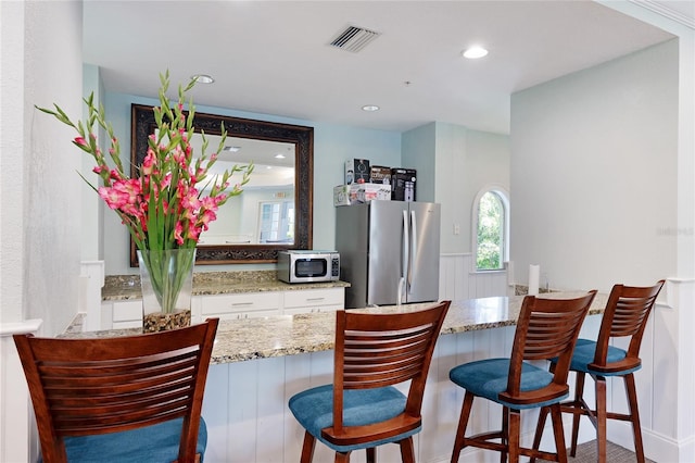 kitchen featuring light stone counters, visible vents, recessed lighting, white cabinets, and appliances with stainless steel finishes