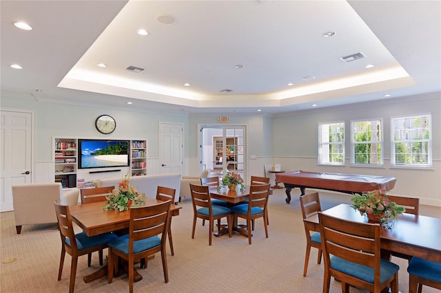 dining room with visible vents, a raised ceiling, light colored carpet, and ornamental molding