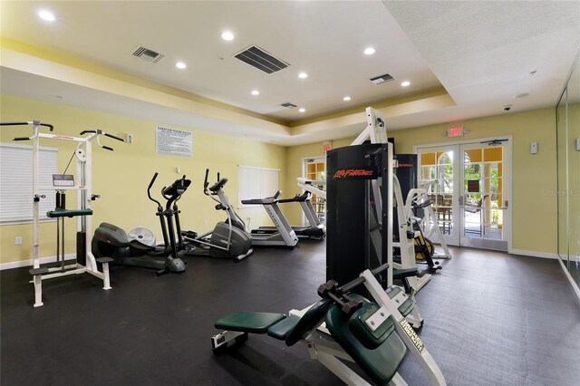 workout area featuring visible vents, french doors, a tray ceiling, and baseboards