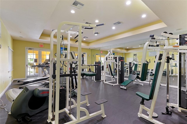 workout area featuring a tray ceiling, visible vents, and french doors