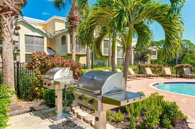 pool featuring a patio area, grilling area, and fence