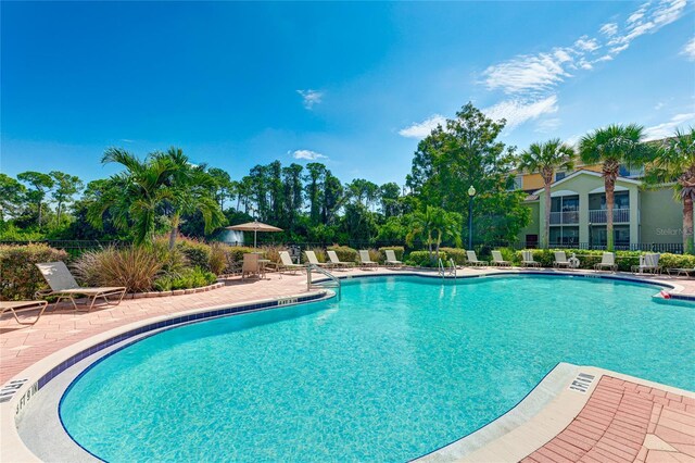 community pool with a patio and fence