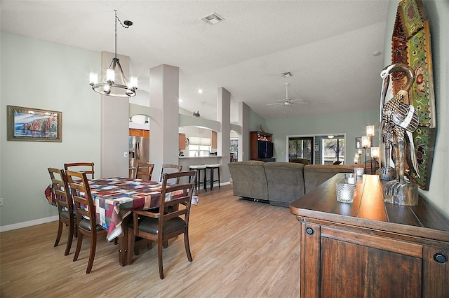 dining space with arched walkways, ceiling fan with notable chandelier, visible vents, baseboards, and light wood-style floors