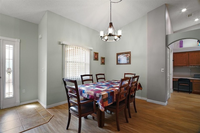 dining area featuring light wood-style floors, visible vents, baseboards, and vaulted ceiling