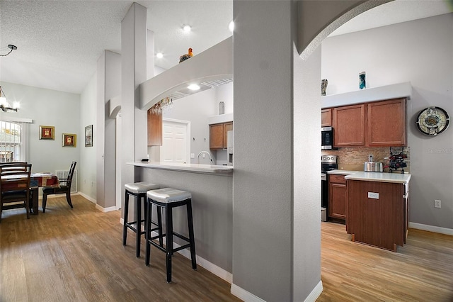 kitchen featuring arched walkways, stainless steel appliances, a breakfast bar, and light wood-style flooring