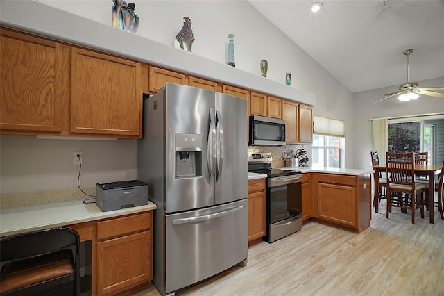 kitchen with vaulted ceiling, light countertops, appliances with stainless steel finishes, and a peninsula