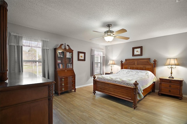 bedroom featuring light wood-type flooring, ceiling fan, baseboards, and a textured ceiling