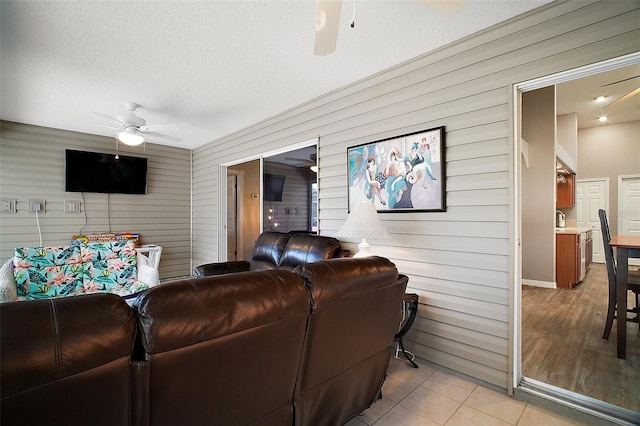 living area featuring light tile patterned floors, a textured ceiling, and a ceiling fan