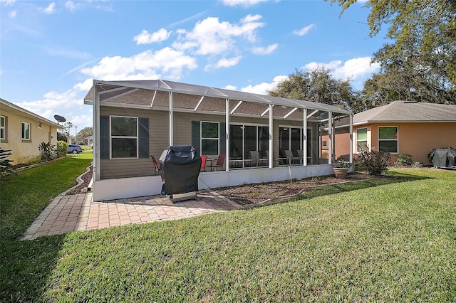 rear view of house with glass enclosure, a yard, and a patio