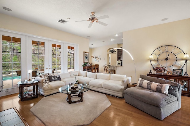 living room featuring a ceiling fan, visible vents, hardwood / wood-style floors, and french doors