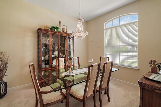 dining room featuring a chandelier, light carpet, and baseboards