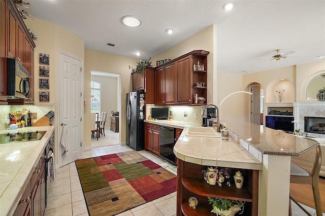 kitchen with a peninsula, a sink, black appliances, tile counters, and open shelves