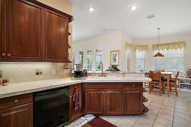 kitchen featuring light tile patterned floors, a peninsula, a sink, black dishwasher, and tasteful backsplash